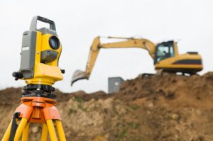 Surveyor equipment in front of working construction machinery loader