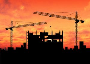 Construction of tall building with 2 cranes at sunset