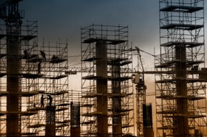 Construction of 3 tall buildings with a crane at dusk